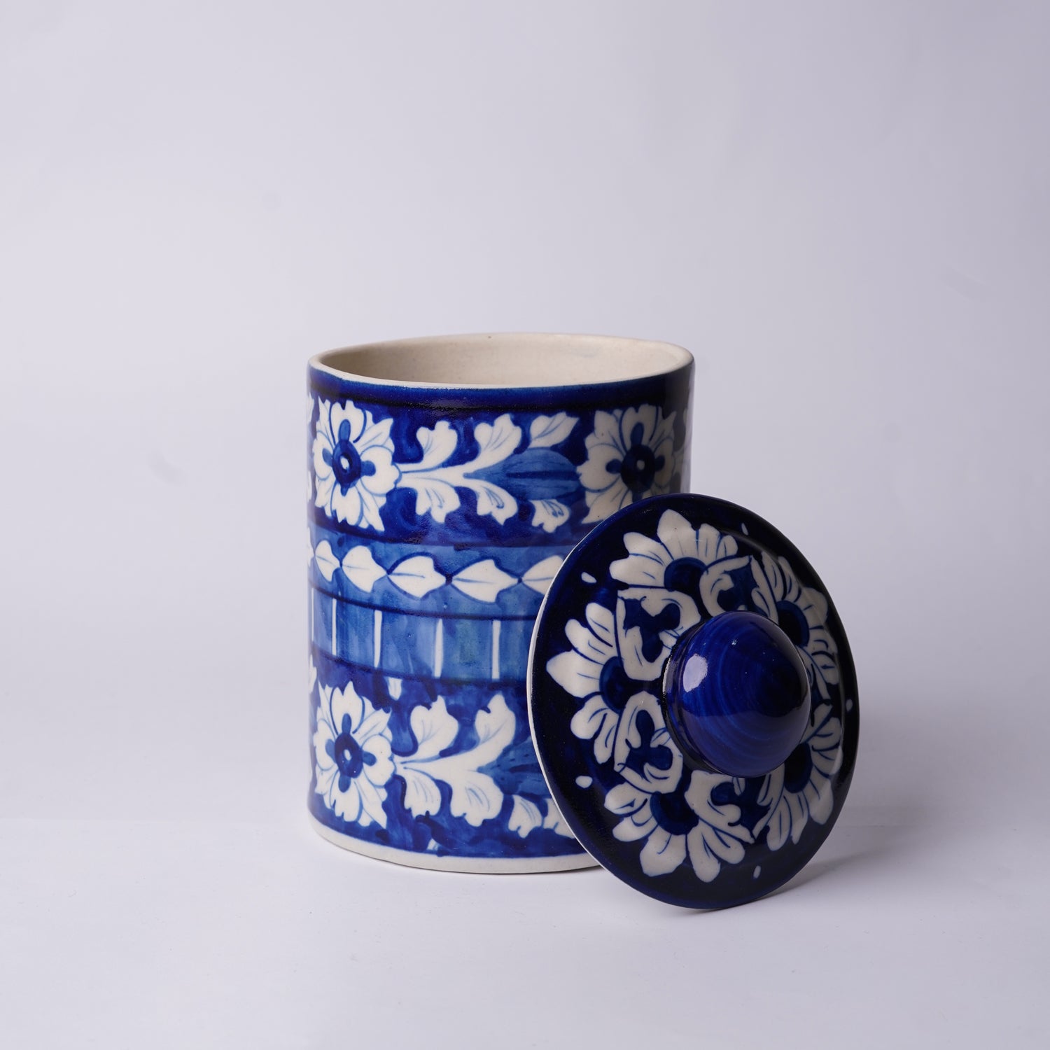 Blue and white ceramic Multani Blue Pottery jar with lid on a light gray background