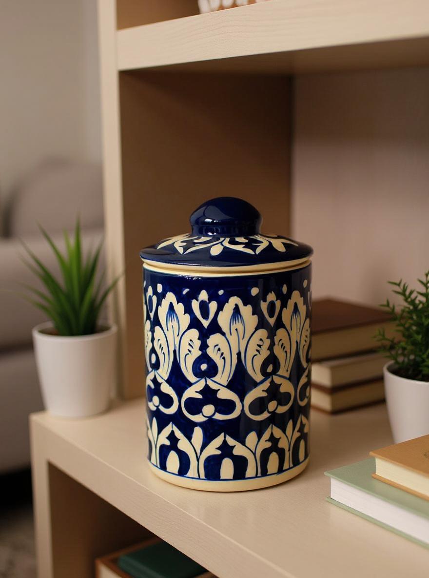 A blue and white patterned Multani blue pottery jar sits on a wooden shelf alongside books and plants.