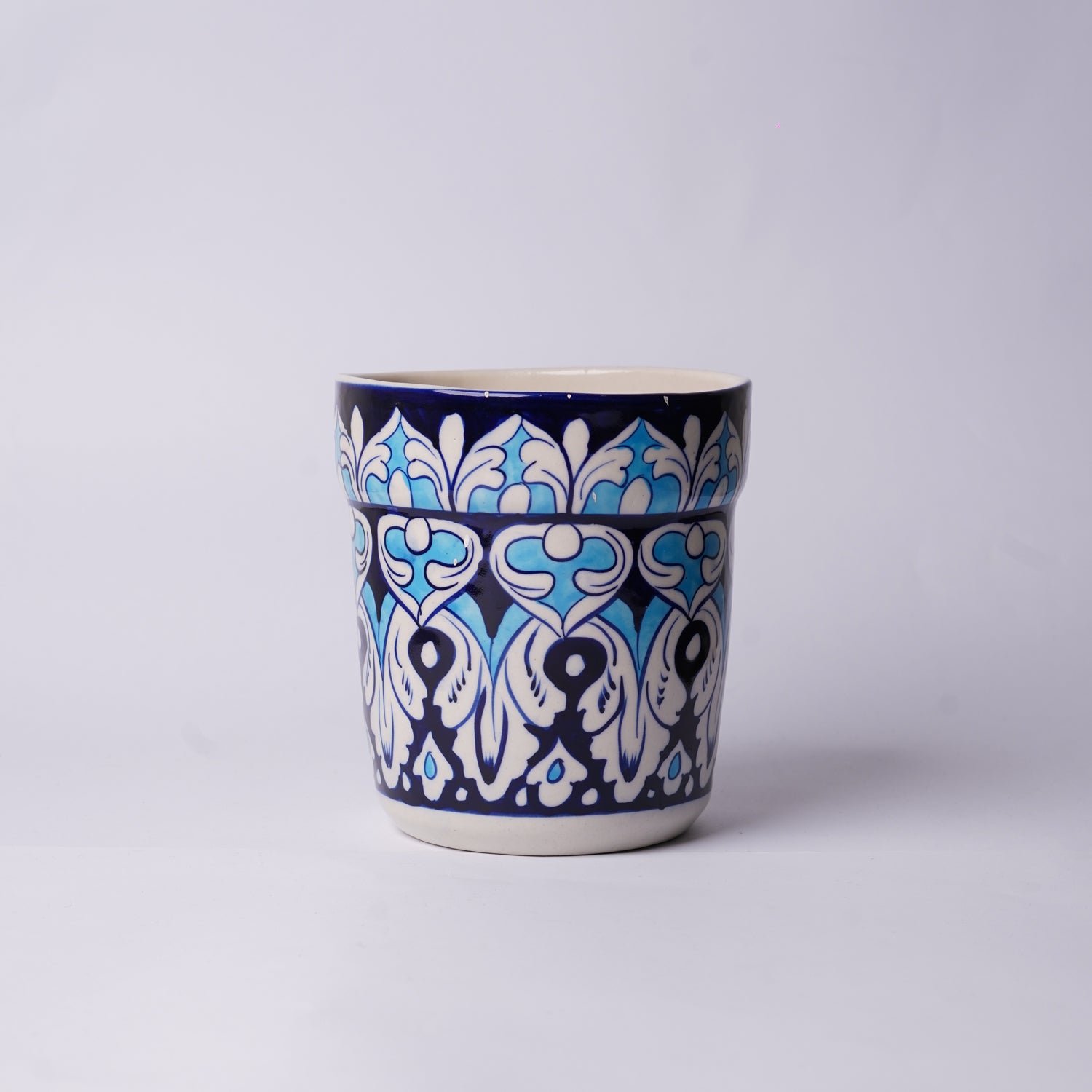Ceramic blue pottery planter with blue and white pattern on a light gray background