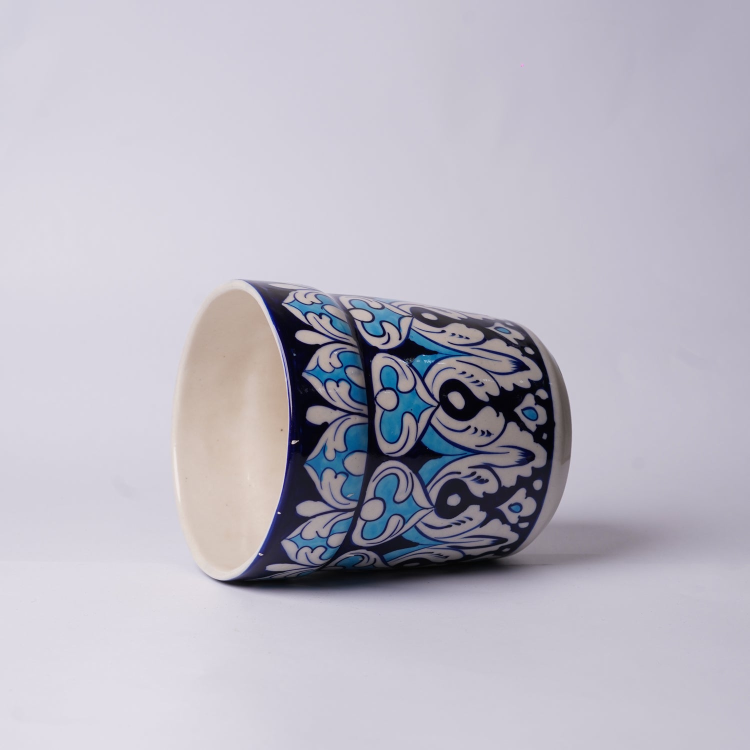 Ceramic cup with blue and white floral pattern on a light gray background