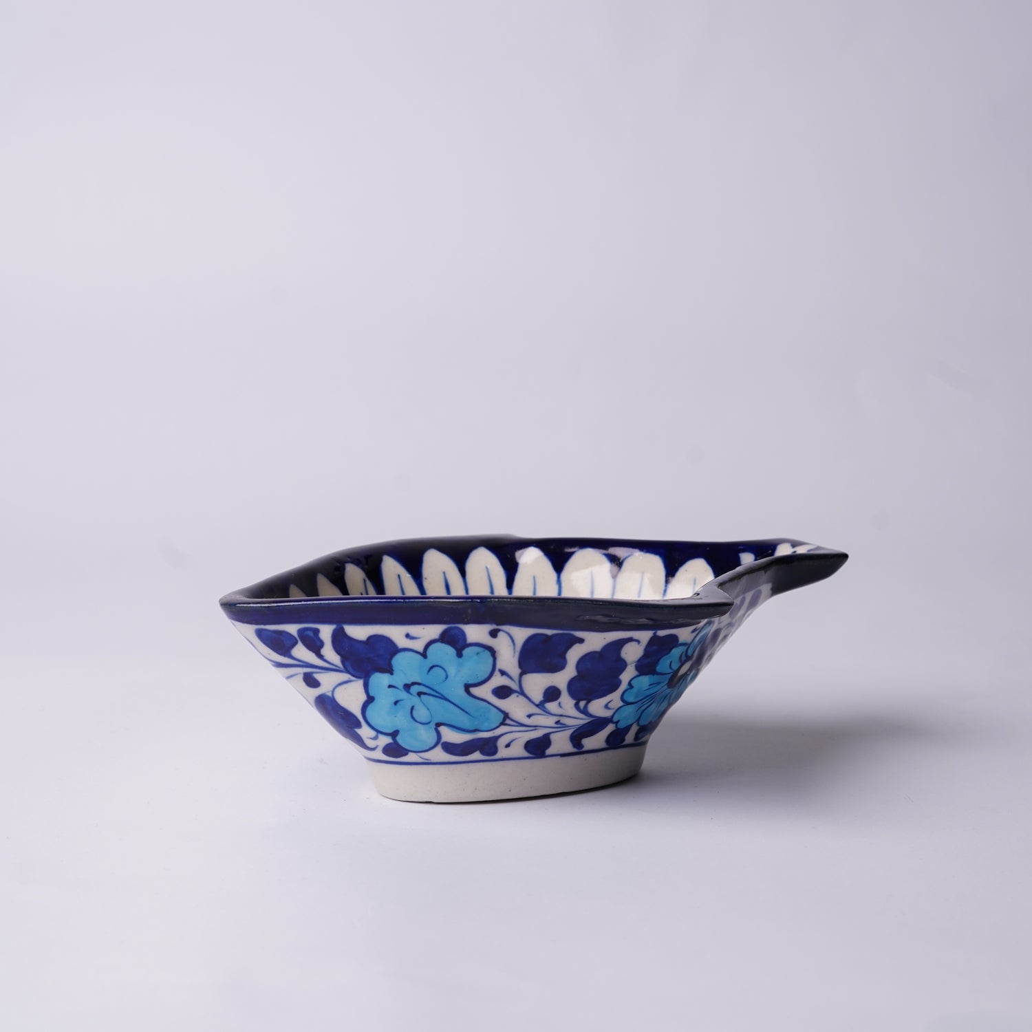 Ceramic multani blue pottery fish-shaped bowl with blue floral design on a white background