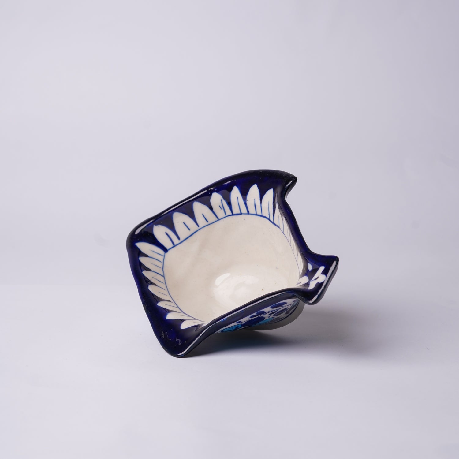 Ceramic blue pottery fish-shaped bowl with blue and white design on a light gray background