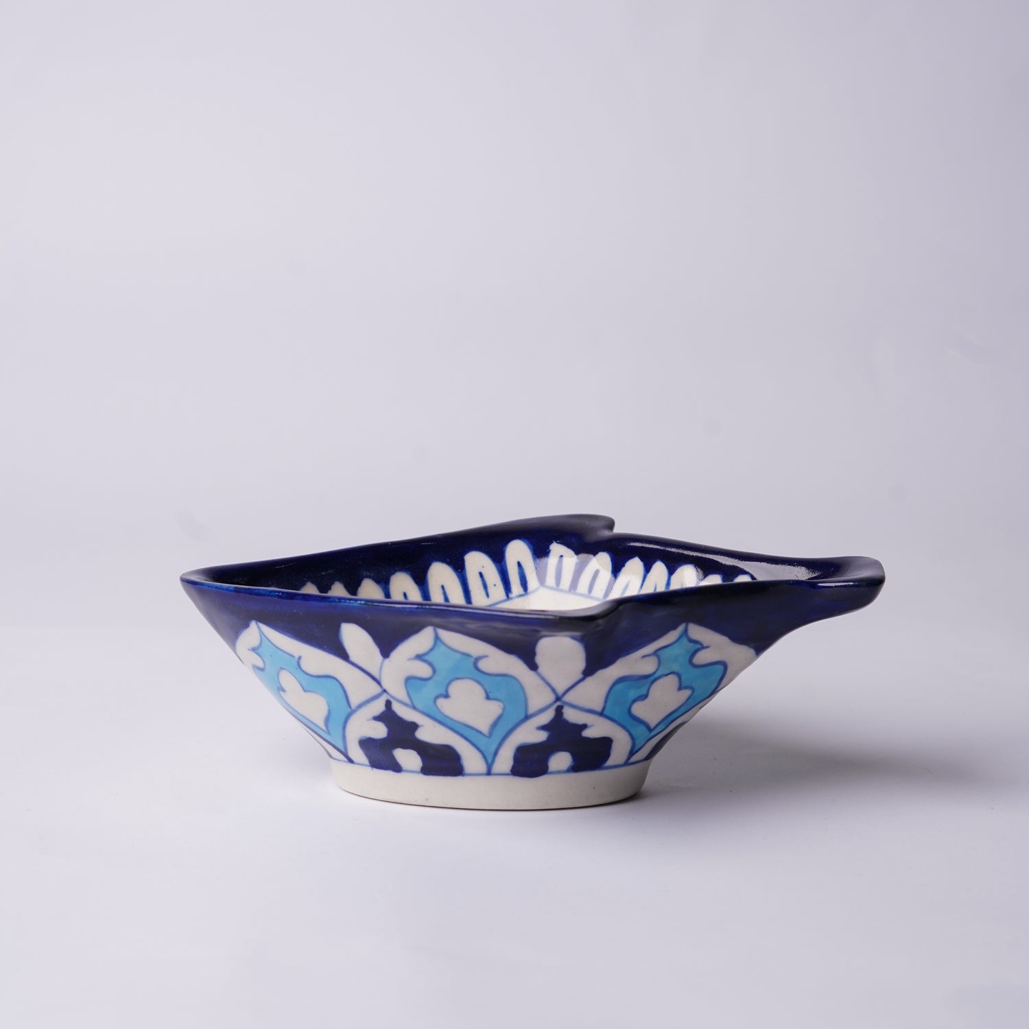 Ceramic blue pottery fish-shaped bowl with blue and white pattern on a light gray background