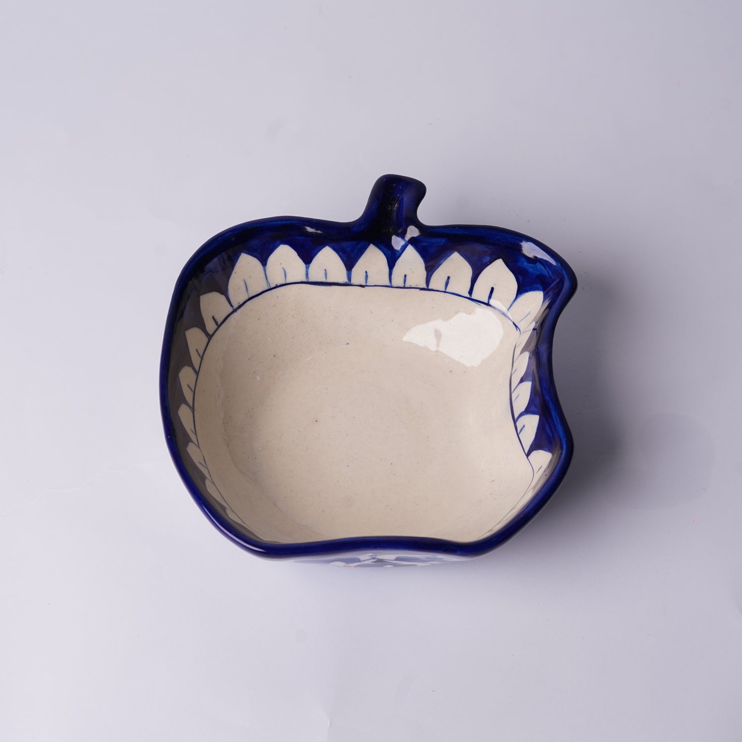 Ceramic multani blue pottery bowl shaped like a leaf with blue rim and white interior on a light gray background