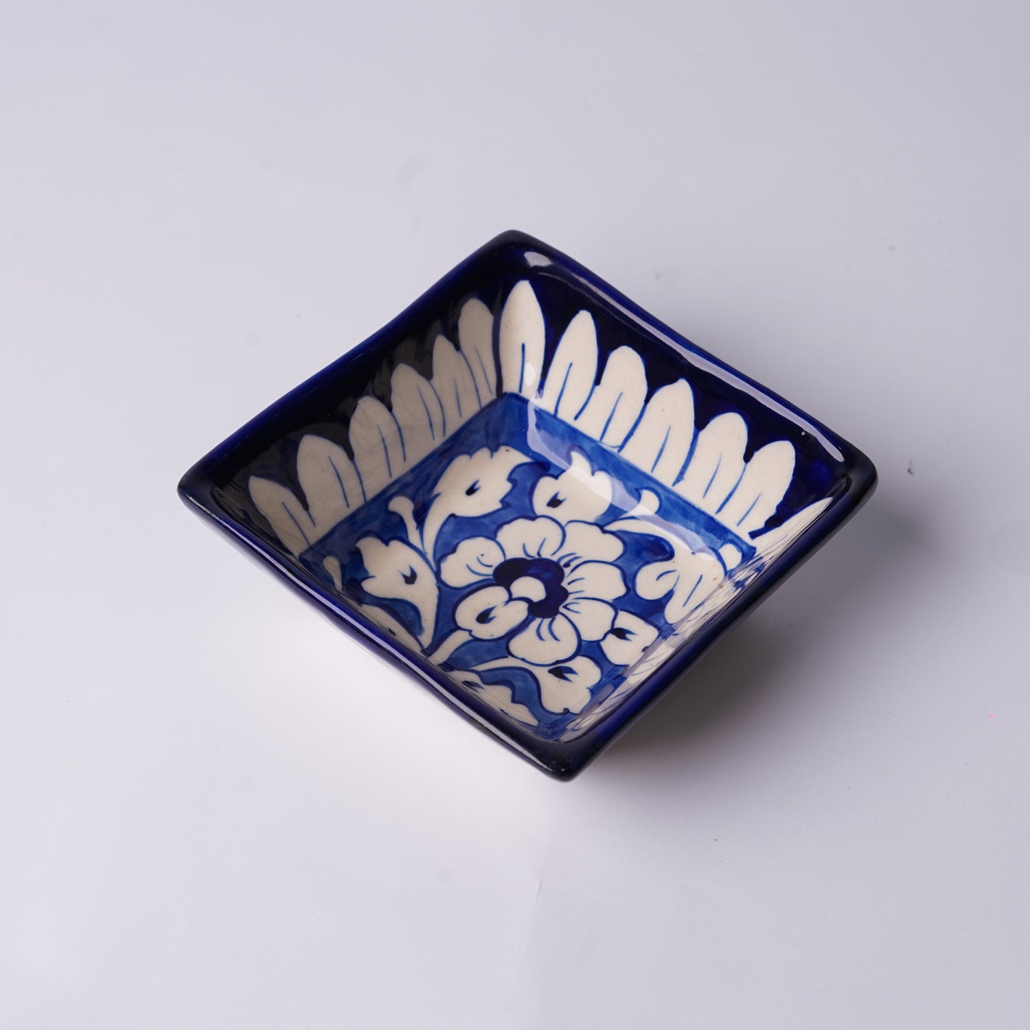 Blue and white ceramic dish with floral patterns on a light gray background, multani blue pottery