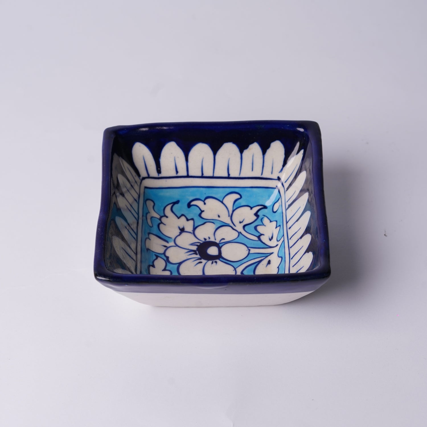 Blue ceramic dish with white floral patterns on a light gray background