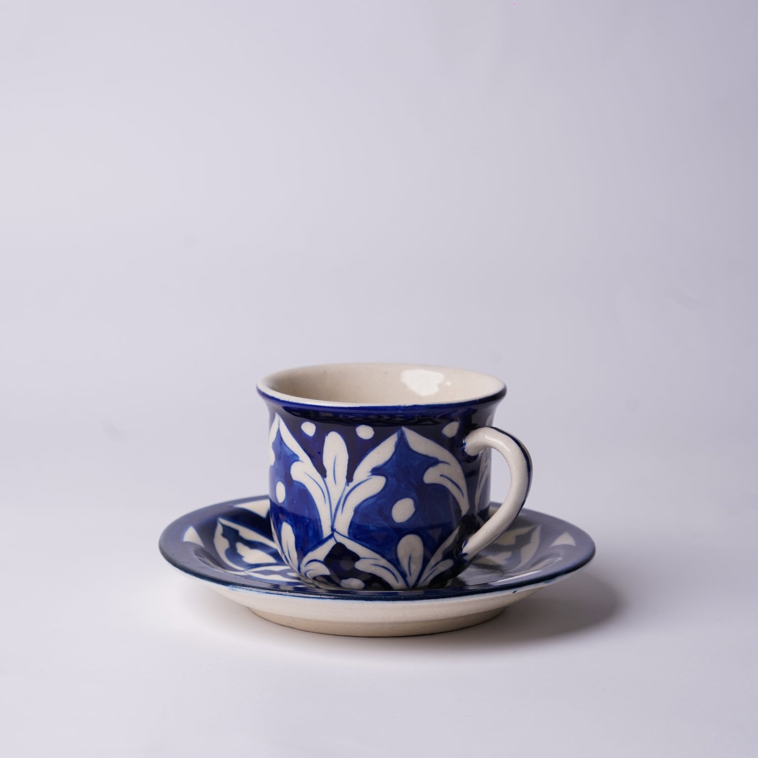 Ceramic  multani blue pottery cup and saucer with blue and white floral pattern on a light gray background