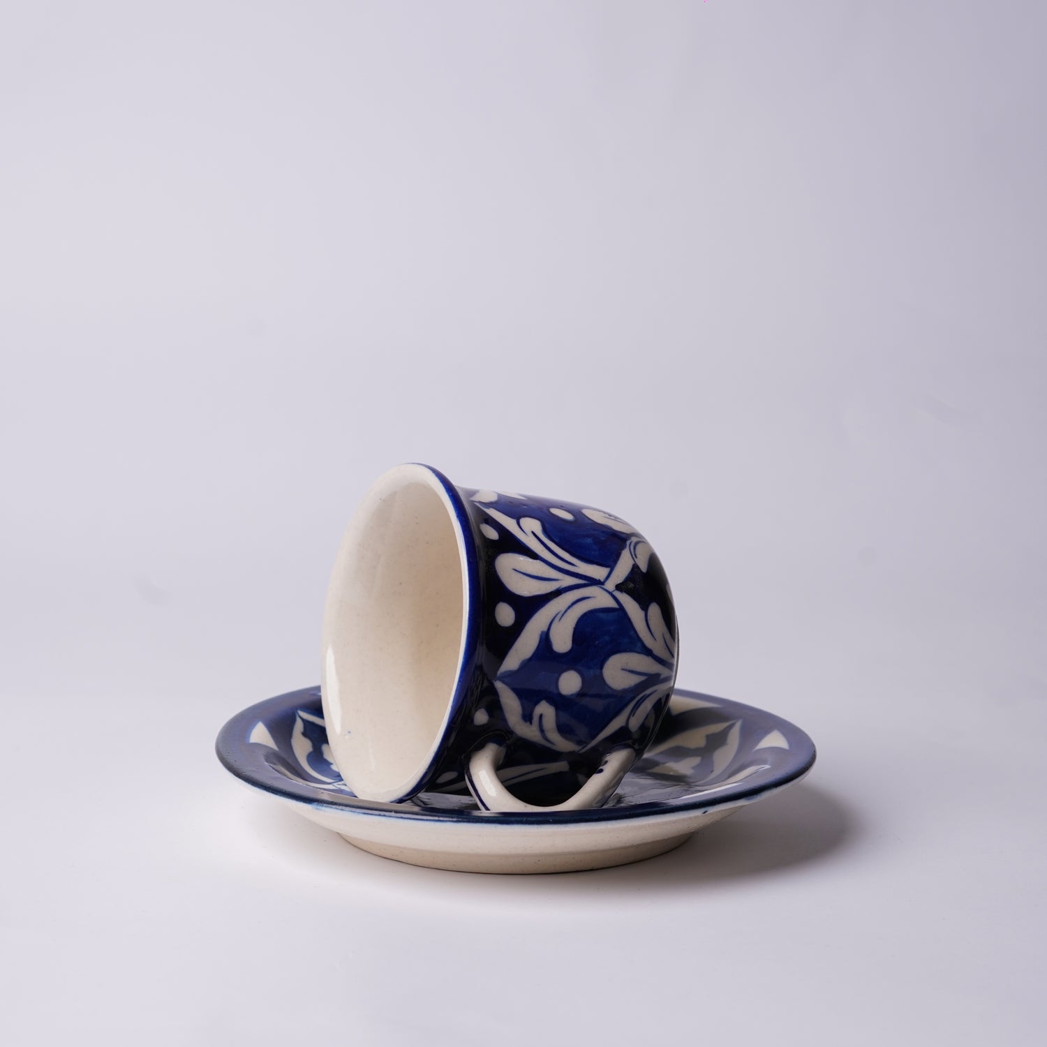 Ceramic  multani blue pottery cup and saucer with blue floral pattern on a white background