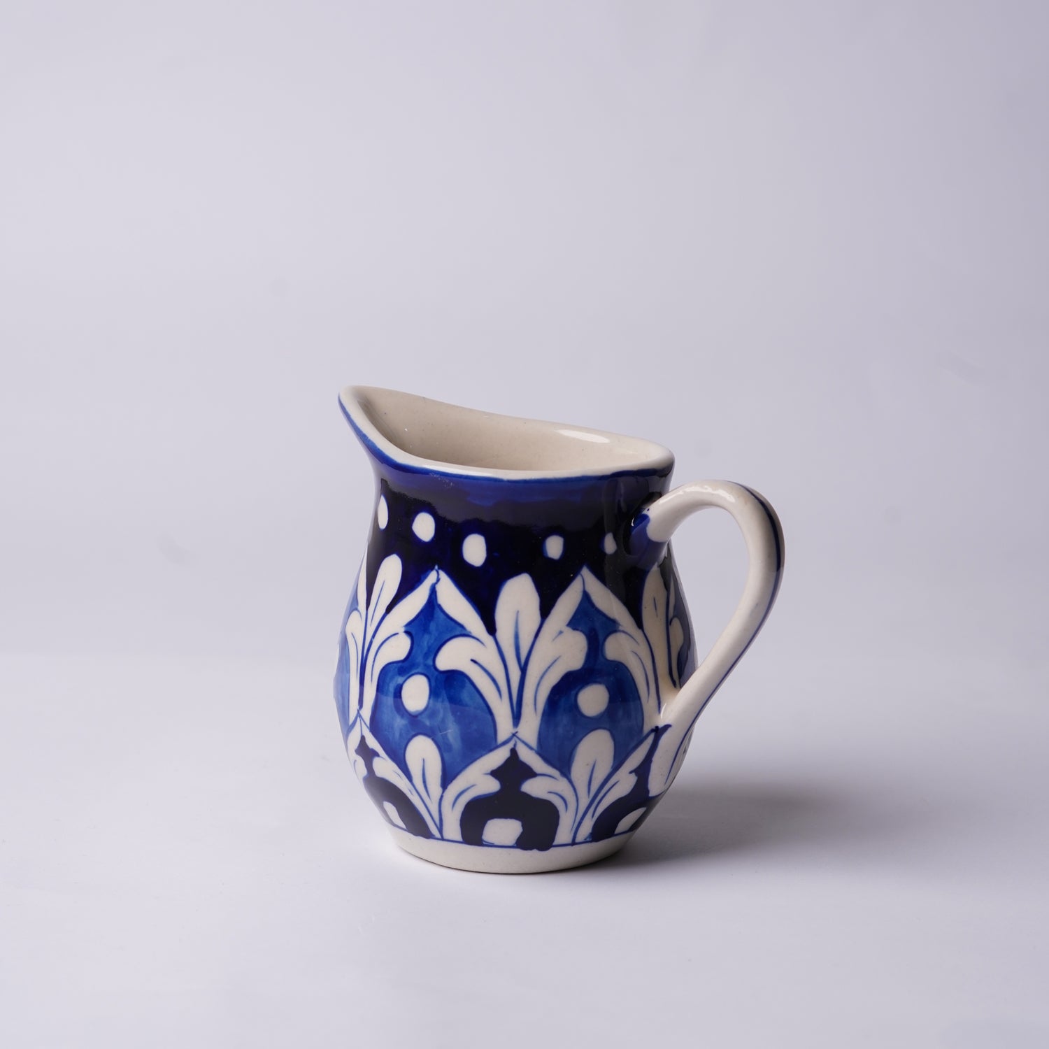 Ceramic  multani blue pottery milk pot with blue and white floral pattern on a light gray background