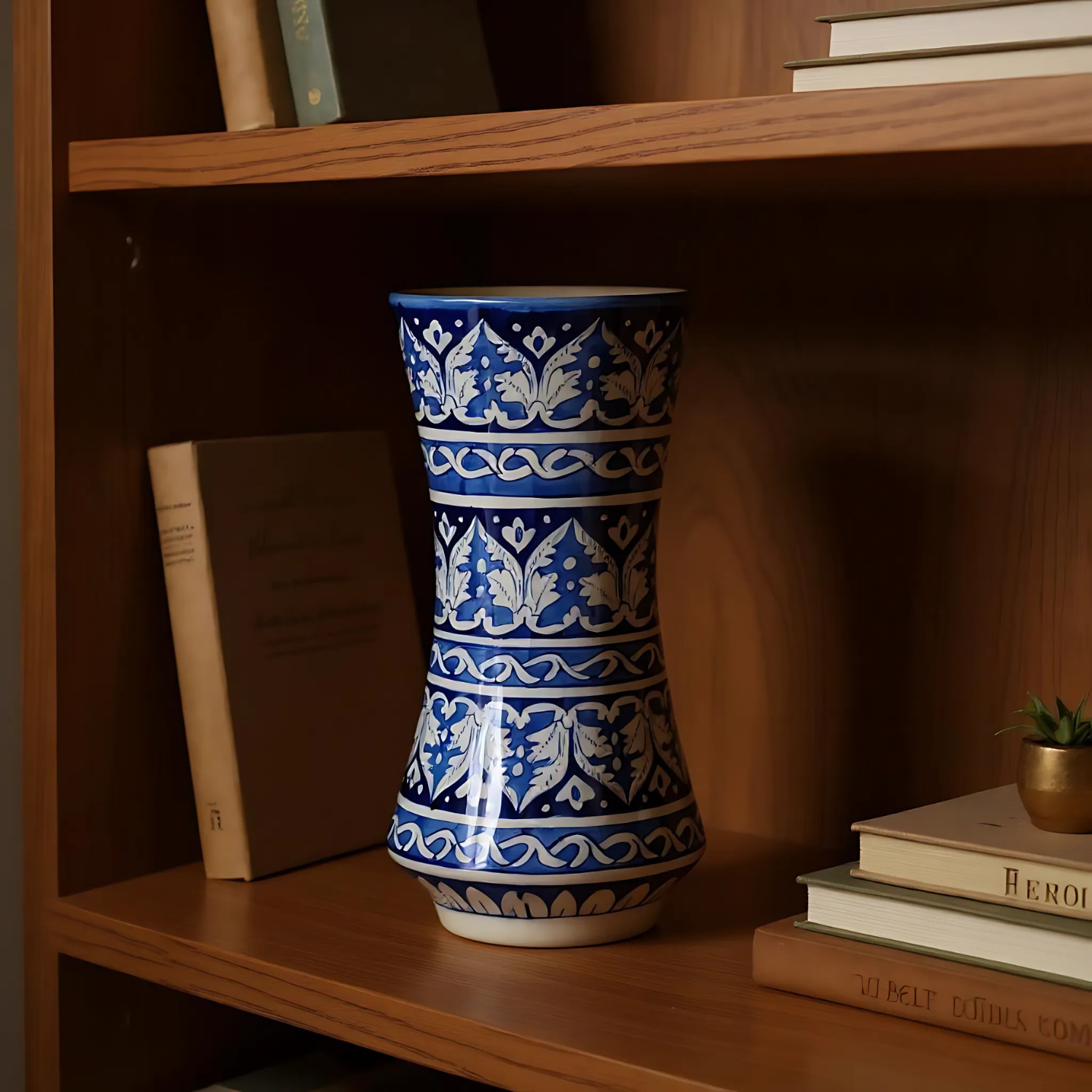 Blue and white patterned Multani blue pottery vase on a wooden shelf with books