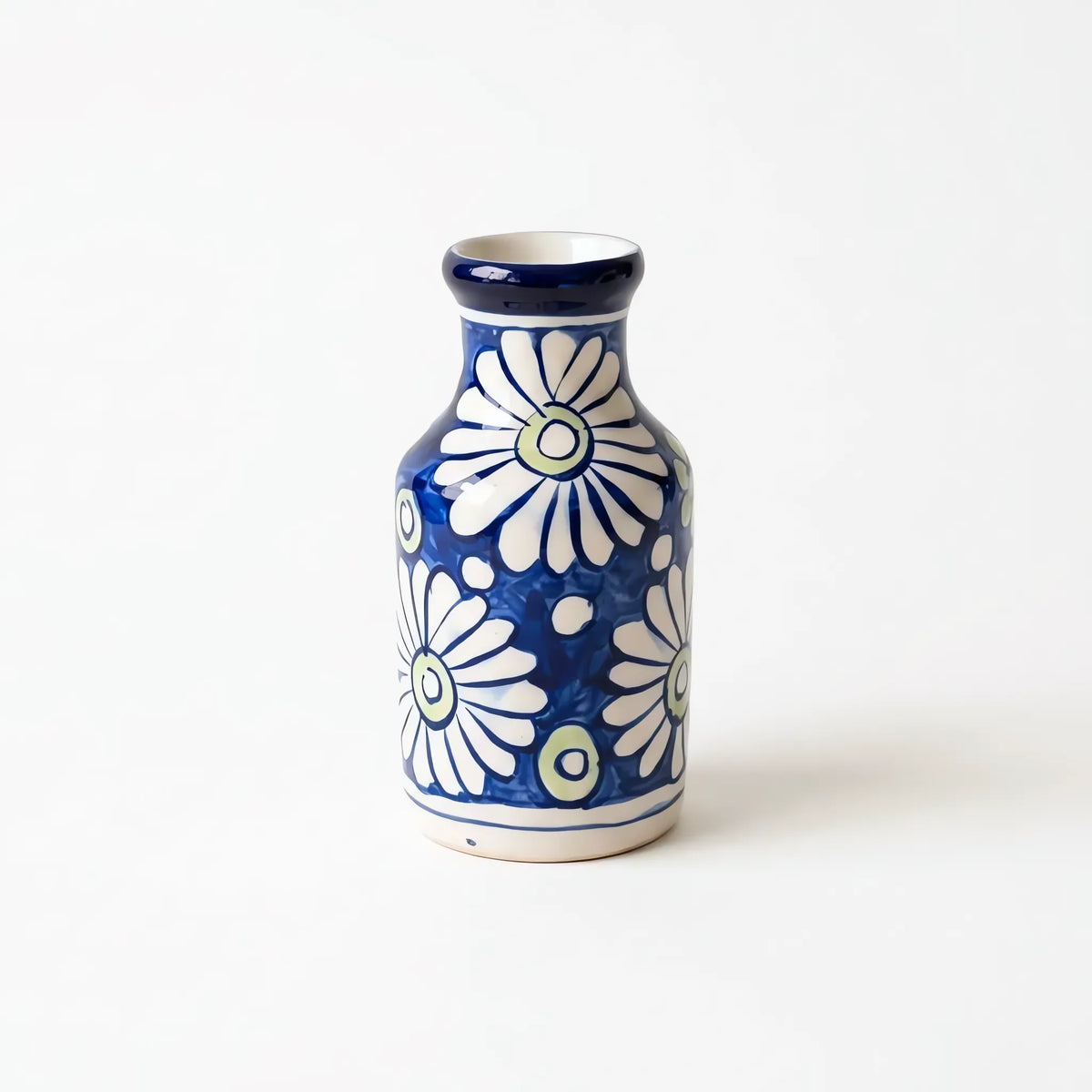 Close view of the blue pottery bottle vase with white daisies and green centres