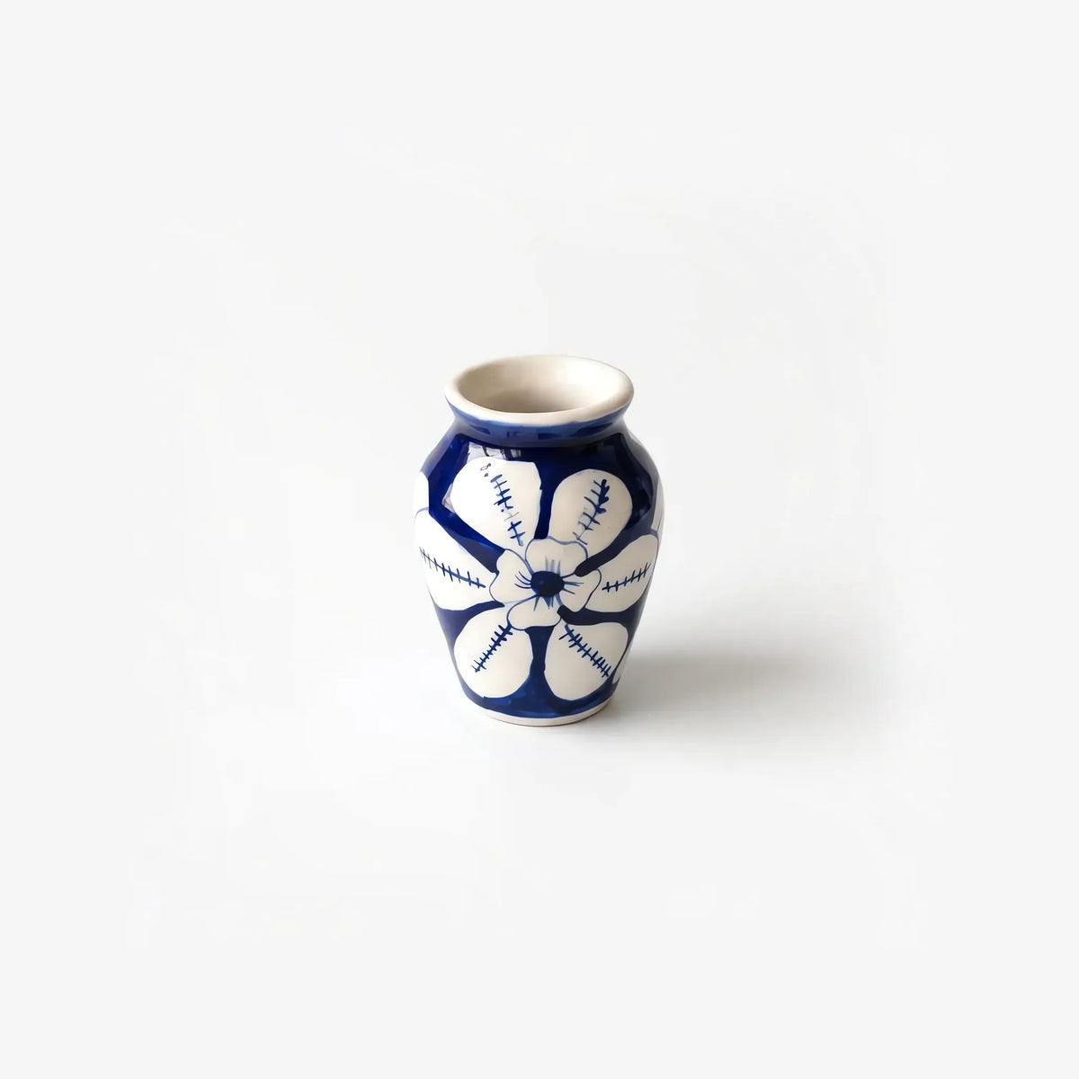 4 inch blue pottery mini vase with one large white flower on cobalt