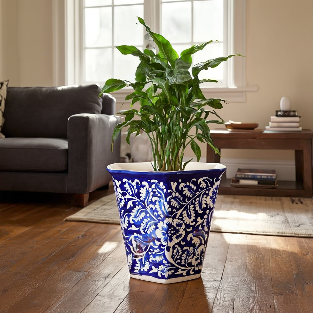 Blue and white patterned Multani Blue pottery planter with a green plant on a wooden floor in a living room.